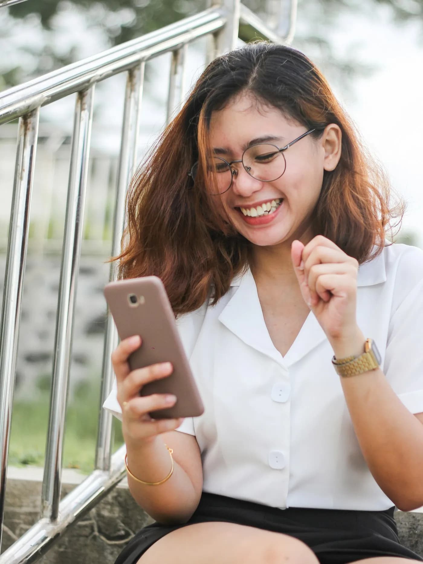 Woman smiling while using her phone outdoors